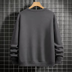 Black crewneck sweatshirt featuring two vertically stacked circular Dragon Ball Z 'Go' Kanji symbols (one orange, one white), flat lay on grey background.
