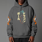 Black pullover hoodie with orange Goku silhouette on chest and vintage 1984 Dragon Ball graphics on sleeves, worn by model on grey background.